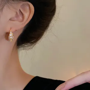 Close-up detail of a gold-plated geometric hoop earring with sparkling zircons on ear
