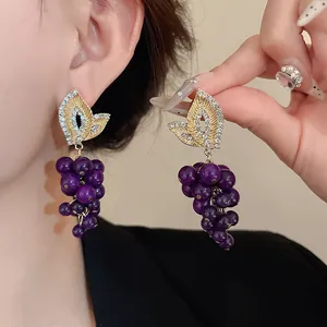 Dettaglio degli orecchini vintage in oro con uva viola e cristalli scintillanti