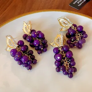 Primo piano dettagliato di orecchini a uva vintage con perline viola e strass.
