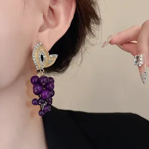 Eleganti orecchini vintage a grappolo d'uva con dettaglio foglia di strass su modella