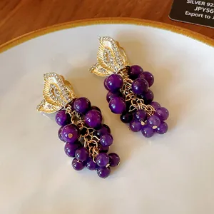 Dettaglio di orecchini vintage a grappolo d'uva con pietre viola.