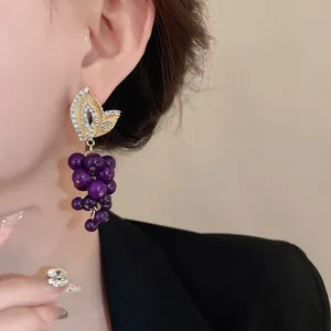 Primo piano di orecchini vintage a grappolo d'uva viola con dettaglio in strass