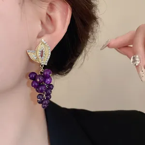 Primo piano dettagliato di orecchini a grappolo vintage con pietre viola e foglia d'oro