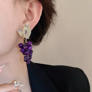 Vista dettagliata di orecchini a uva vintage con strass e pietre artificiali viola