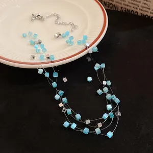 Detail of multi-layer necklace featuring blue cat-eye square beads and silver cubes