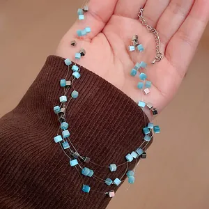 Detailed macro shot of multi-layer necklace featuring blue square cat eye stones on a palm