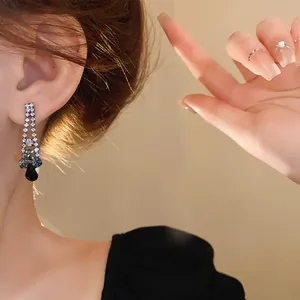 Close-up detail of a silver earring with sparkling rhinestones and a black teardrop gem