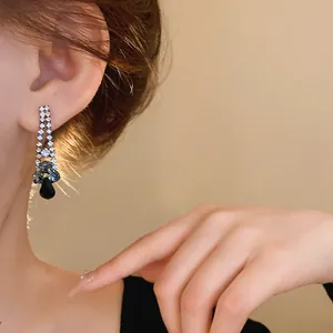 Close-up detail of elegant black water drop rhinestone earrings worn by a model