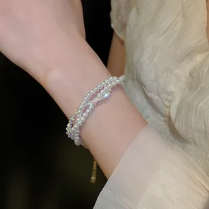 Detailed view of an elegant multi-layer pearl and crystal bracelet on a female wrist.