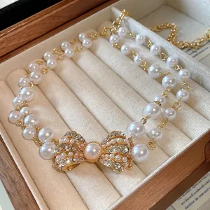 Collana a doppio filo di perle artificiali con un elegante pendente fiocco strass.