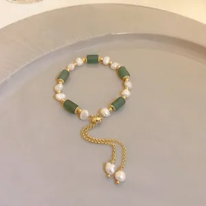 Detail view of pearl bracelet with green cylindrical stones and adjustable gold chain