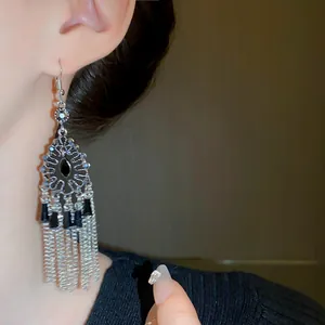 Primo piano di orecchini vintage con nappe geometriche in metallo e strass lucidi
