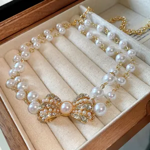 Dettaglio ravvicinato della collana a doppio giro di perle sintetiche con ciondolo a fiocco