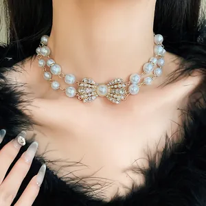 Dettaglio di una collana di perle a doppio strato con fiocco di strass su una modella