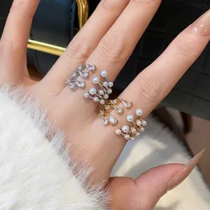 Elegant multi-layer open ring with pearls and zircons featured on model's hand.