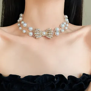 Primo piano di una collana di perle a doppio filo con un fiocco di strass scintillanti.