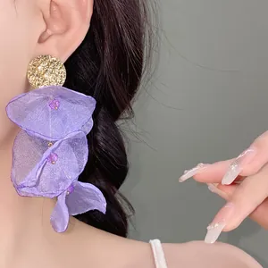 Detailed view of elegant purple chiffon flower earrings with textured gold studs.