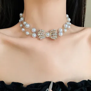 Vista dettagliata di una collana di perle a doppio strato con un fiocco di strass.