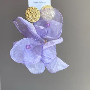 Detailed macro shot of elegant purple chiffon fabric flower drop earrings with gold textured studs