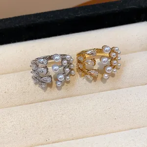 Detailed view of elegant silver and gold layered rings with zircons and pearls.