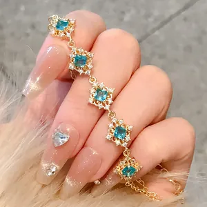 Close-up of an elegant gold bracelet with rhombic floral patterns and cyan zircons.