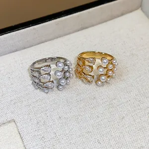 Close-up detail of silver and gold open rings with pearls and pear-shaped zircons