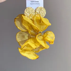 Detail view of yellow chiffon petal tassel earrings with golden hammered studs