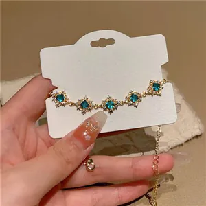 Close-up of elegant gold bracelet featuring emerald green zircon flower charms.