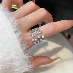 Close-up detail showing a silver-tone multi-layer open ring with zircons and white pearls