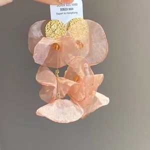 Close-up detail of pleated peach chiffon flower tassel earrings with golden studs