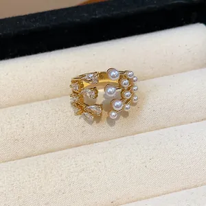 Close-up of gold multilayer ring featuring elegant teardrop zircons and white pearls.