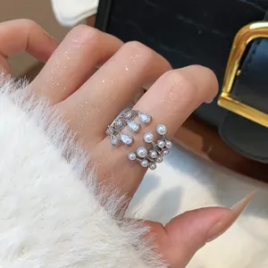Detailed close-up view of an elegant zircon and pearl multi-layer open ring on a female finger