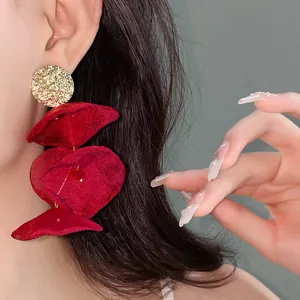 Close-up of elegant red chiffon flower drop earrings with textured gold studs