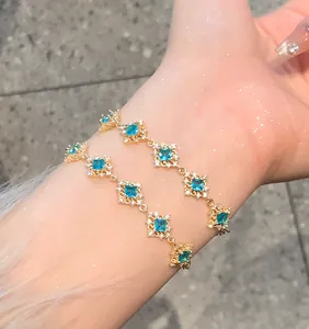 Elegant gold charm bracelet with rhombus-shaped blue zircon flowers worn on wrist