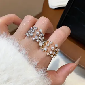 Macro detail view of multilayer zircon and pearl open rings worn on a hand index finger