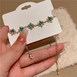 Close-up of emerald green zircon rhombus flower pattern on gold bracelet