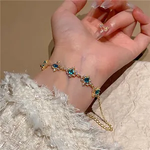 Close-up of elegant gold zircon bracelet with turquoise rhombus flower charms on wrist
