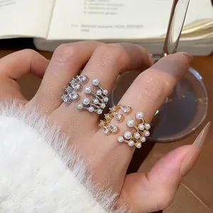 Close-up of multi-layer open rings with zircon and pearls in gold and silver finish