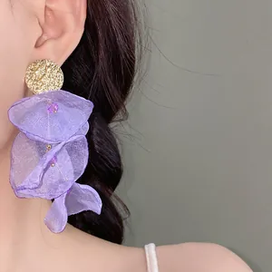 Close-up of elegant purple chiffon flower tassel earrings with gold-textured studs on a model.