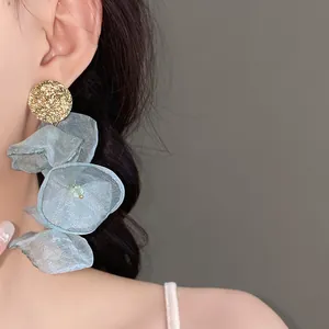 Close-up of light blue chiffon flower tassel earrings featuring golden textured round studs