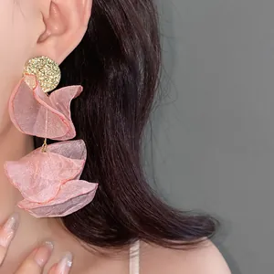 Close-up of elegant pink chiffon flower earrings with hammered gold disc detail on model