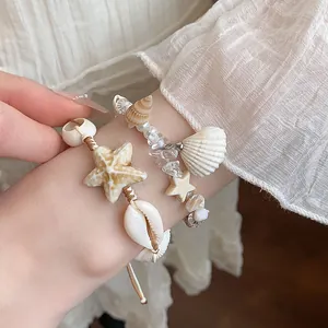 Close-up of handmade starfish and shell beaded bracelets on a wrist for vacation style.