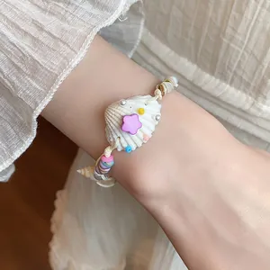 Detailed view of a boho style seashell bracelet featuring pearls and purple star on a wrist
