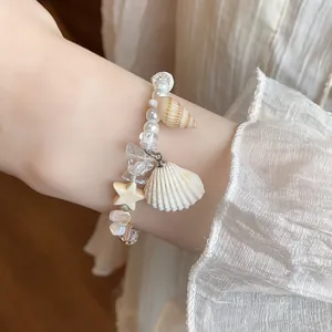 Close-up of handmade beaded bracelet with natural shells and pearls on wrist