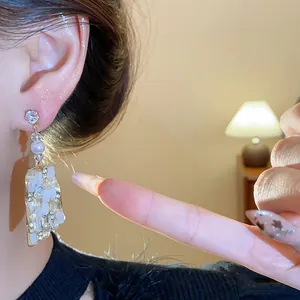 Detaillierte Nahaufnahme von unregelmäßigen quadratischen Ohrhängern mit Strass und Silbernadeln