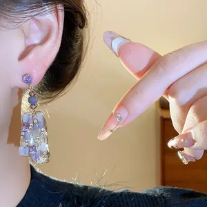 Nahaufnahme von lila Strassohrringen mit unregelmäßigem Glasquadrat und Silbernadel.