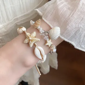 Close-up of bohemian starfish and seashell beaded bracelets on a woman's wrist