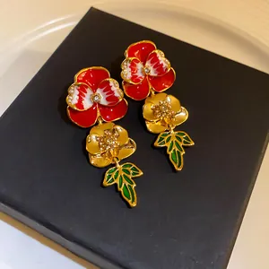 Detailed macro view of vintage red enamel floral drop earrings with gold leaves on black box