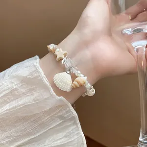 Exquisite close-up showing the detail of a shell and pearl beaded bracelet on a wrist
