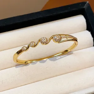 Gros plan d'un jonc doré 18k avec motifs floraux en zircon dans un écrin à bijoux beige